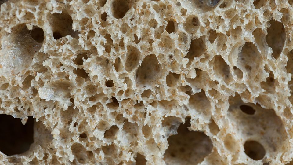 A slice of sourdough bread, up close, its dough and holes visible.
