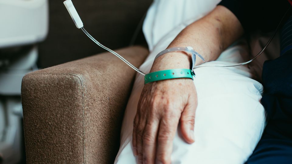 A close-up of a persons arm connected to an IV drip receiving cell therapy.