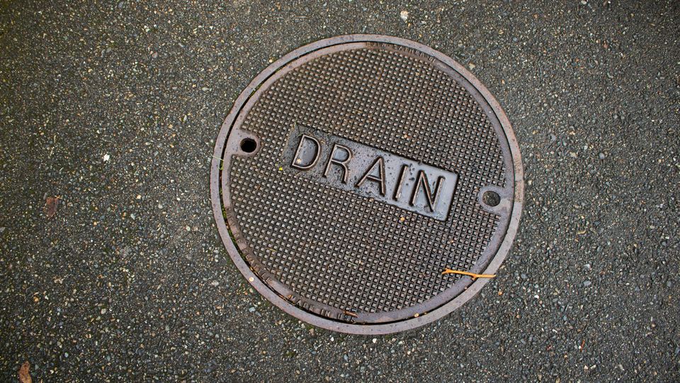 A picture of a storm drain lid in the road.