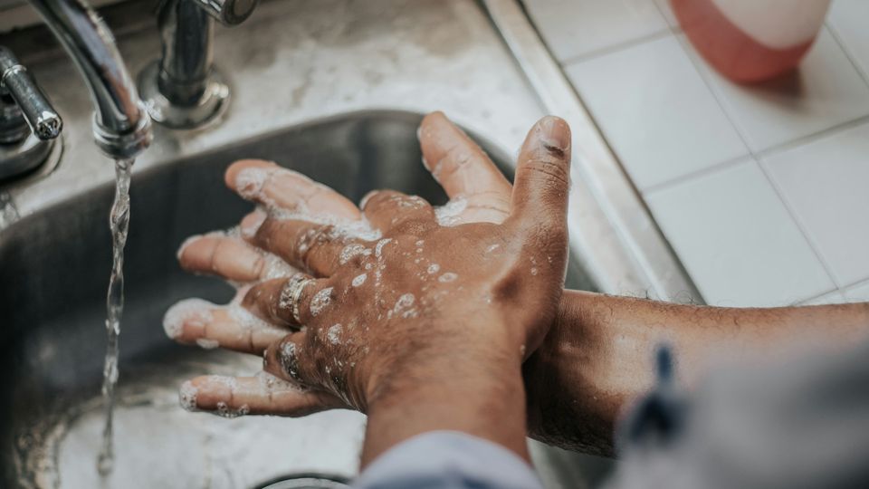 Person washing hands thoroughly with soap at a sink, representing compulsive hand-washing in OCD.