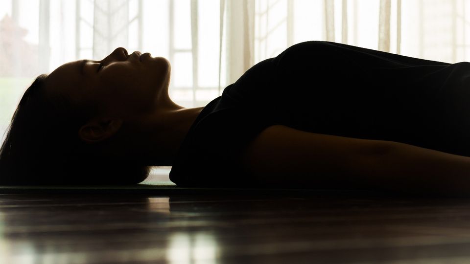 Woman lying on the floor in a dimly lit room, possibly during a ketamine-assisted therapy session.