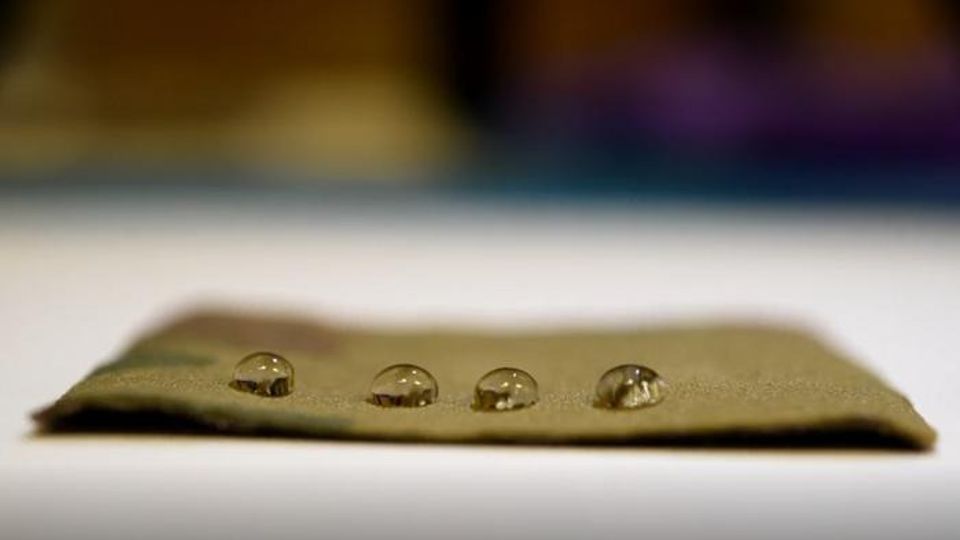 Oil droplets beading on a small, brown square of non-stick material.