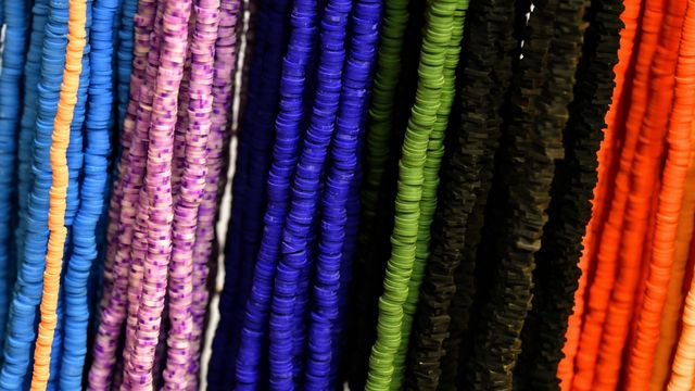 Rows of small polymer beads on strings, all different colors.