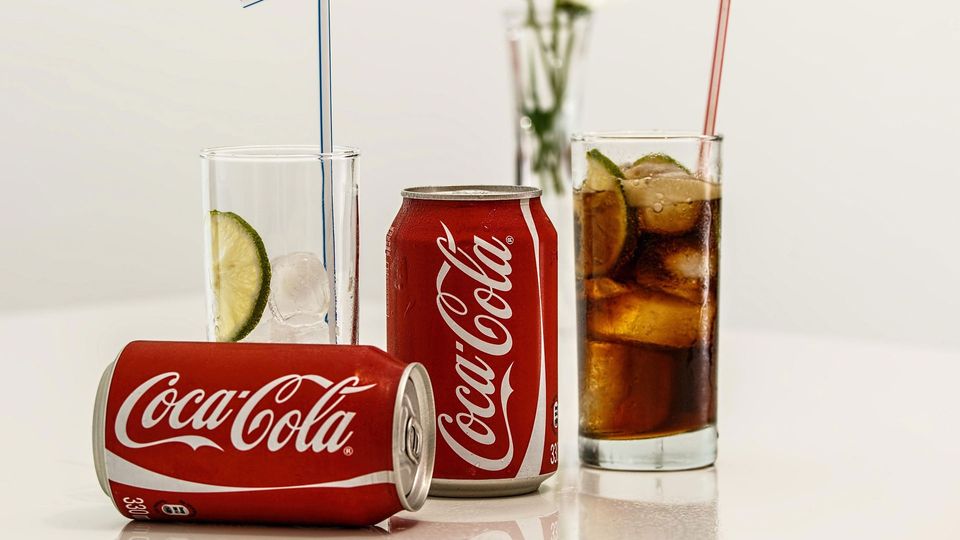 Image of Coca-Cola cans and drink in glass.