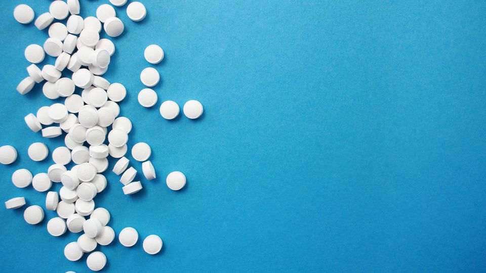 A cluster of white pills on a blue background.