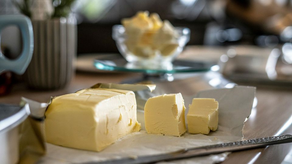 A block of butter, cut into pieces, illustrating a source of dietary fat that influences cancer growth.