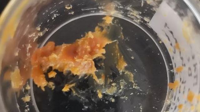 A light brown, sticky residue in a glass jar.
