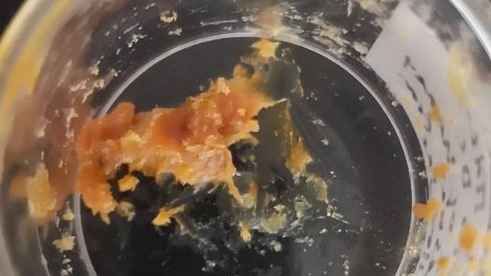 A light brown, sticky residue in a glass jar.