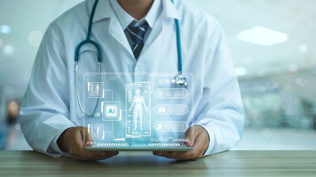 A doctor holding up a small tablet with a hologram floating above it, that shows the letters "AI" and an assortment of different medical images.