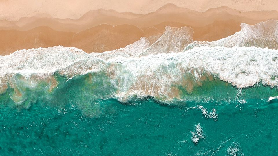 Surf laps onto the sand from a turquoise sea.