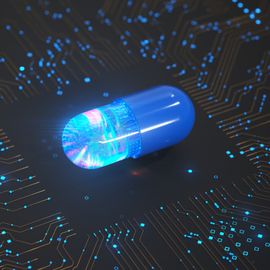 A blue drug pill on top of a black switchboard, representing AI-driven drug discovery. 