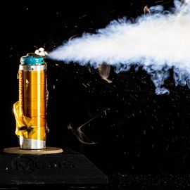 A golden battery that is failing, shooting a jet of smoke out to its right-hand side. 