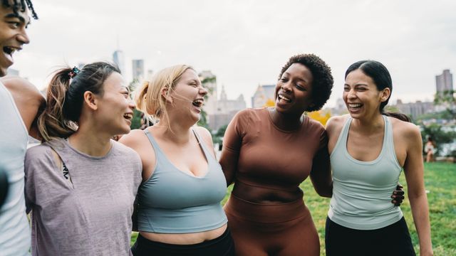 Group of diverse women laughing together in activewear, representing community and support during menopause.