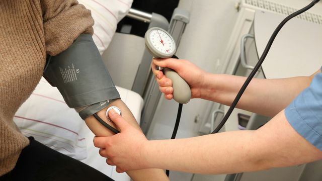 A doctor takes a patient's blood pressure using an inflatable collar.