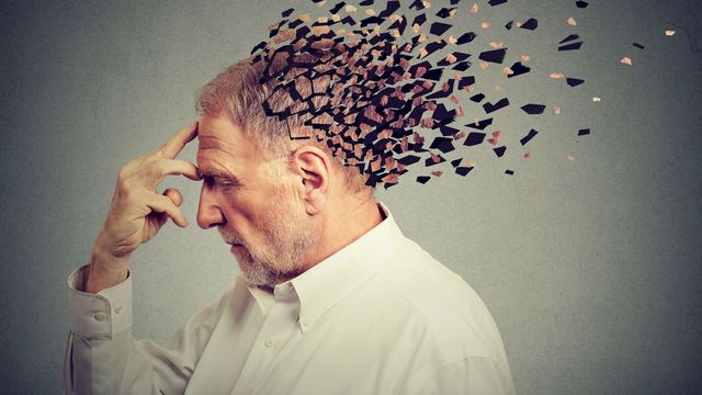Conceptual image of an older man with fragmented particles dispersing from his head, symbolizing brain aging and memory loss.