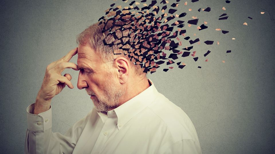 Conceptual image of an older man with fragmented particles dispersing from his head, symbolizing brain aging and memory loss.
