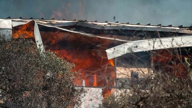 A home consumed by fire, its roof bent and and collapsing.
