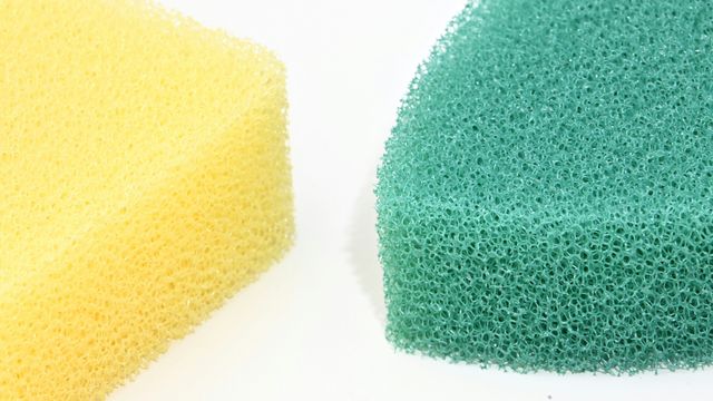 A close-up photograph of a yellow sponge and a green sponge, lying side-by-side.