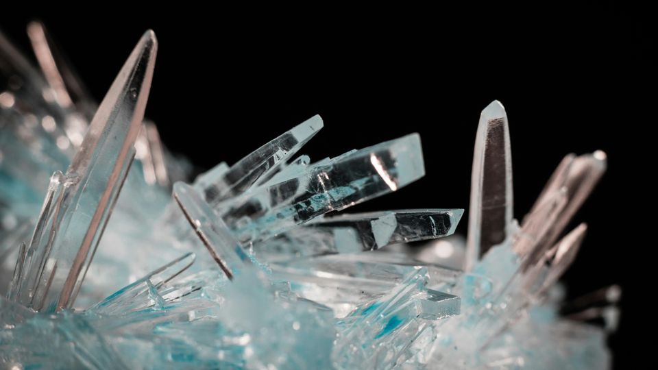White and blue clear crystals against a black background.