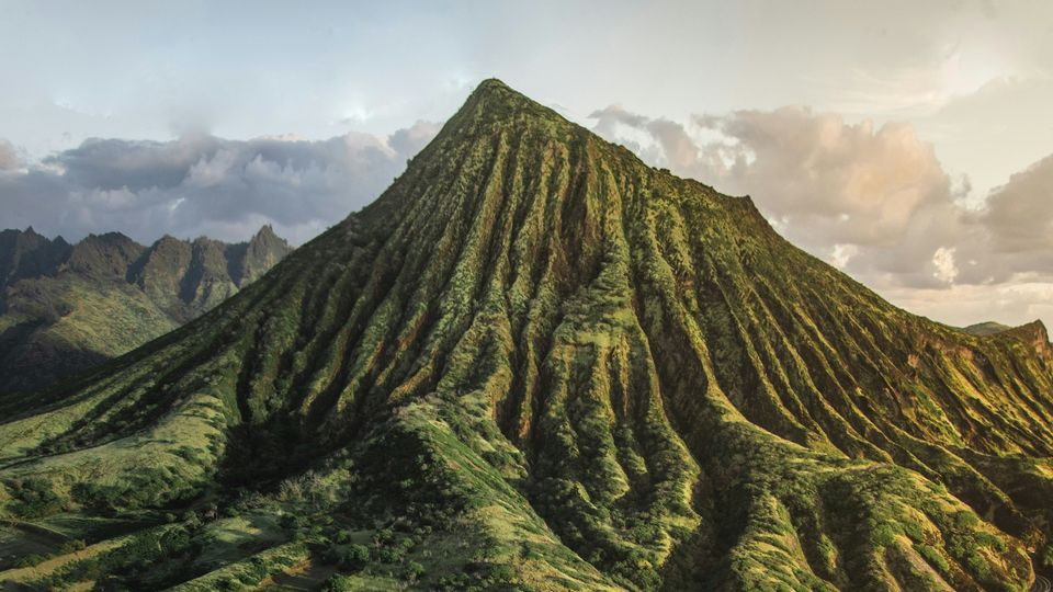 An extinct volcano in Hawai'i, ridged and green, rising into the clear sky.