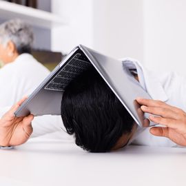 Frustrated scientist holding a laptop over his head in a laboratory. 