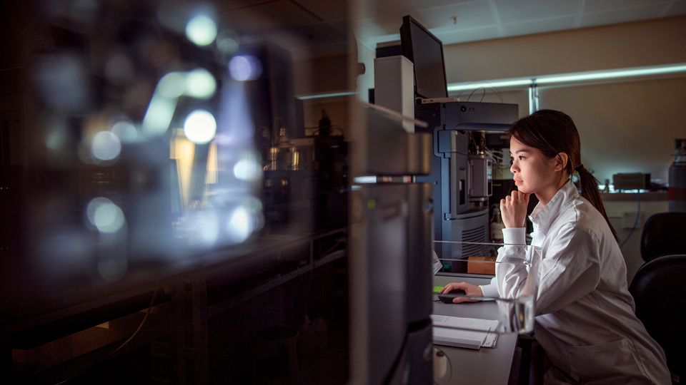 Scientist working with automated laboratory equipment in a research facility.