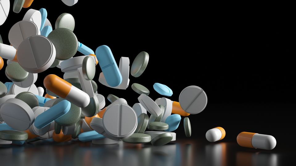 A digital render of different pills and medicines cascading down from the top-left of the image to the bottom-right.