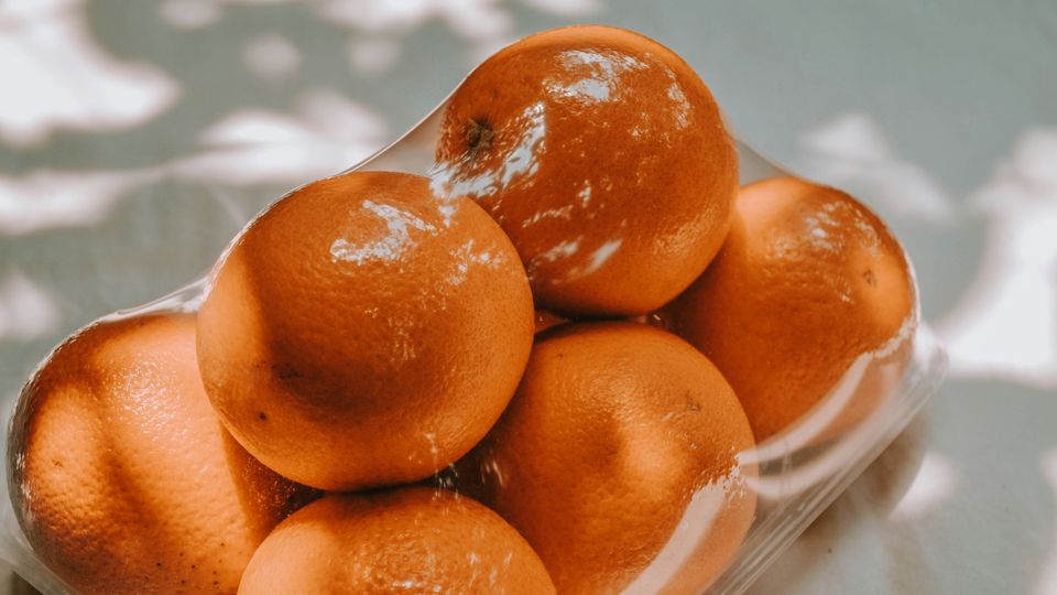 Oranges in a shrink-wrapped plastic tray.