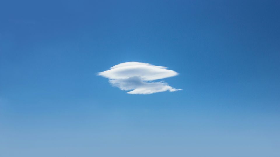 A single cloud in a blue sky.