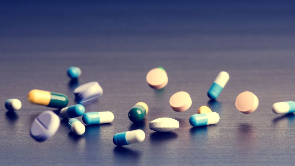 A variety of different pills being spilled onto a table.