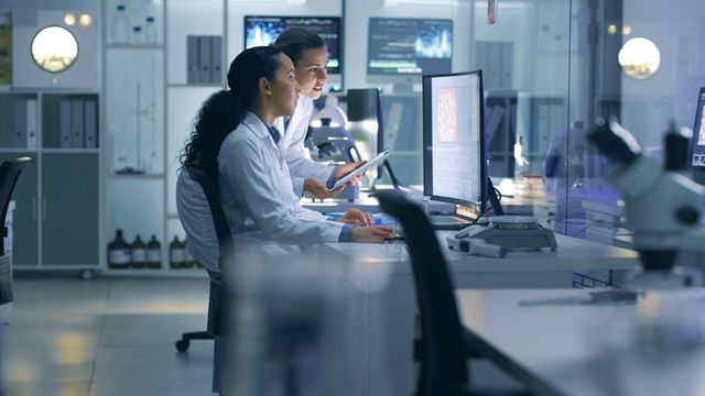 Laboratory team reviewing experiments with advanced equipment, reflecting Thermo Fisher’s US manufacturing expansion.