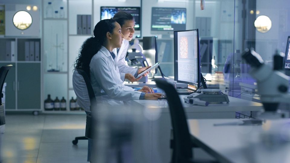 Laboratory team reviewing experiments with advanced equipment, reflecting Thermo Fisher’s US manufacturing expansion.
