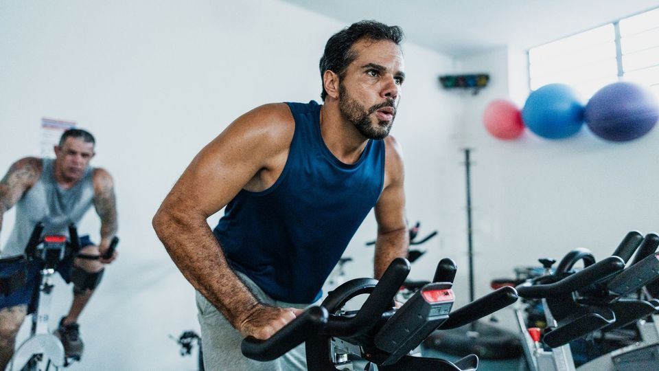 Male athlete training on a stationary bike during an intense indoor cycling workout.