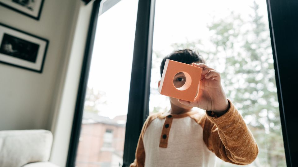 A child with ADHD holding up a toy block.