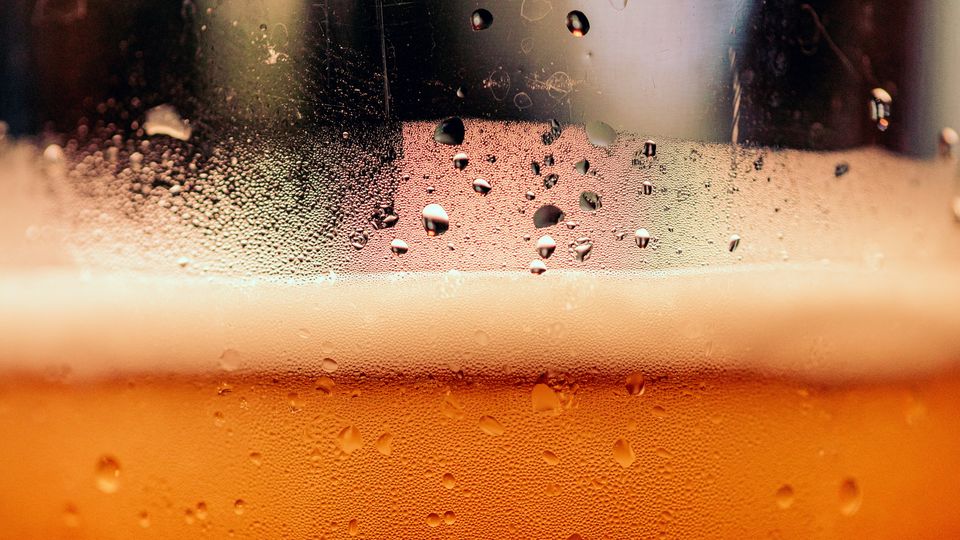 A thin line of beer foam on a glass. Condensation visible.