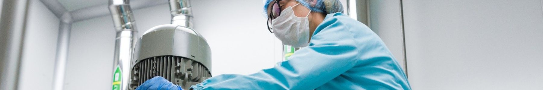 Researcher adjusting controls on a large bioreactor for therapeutic protein production 