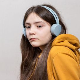 Young girl with headphones wearing a yellow hoodie, representing autism and sensory sensitivity. 