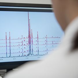 XRD data graphs displayed on a computer screen with the back of a scientist who is looking at it out of focus in the foreground. 