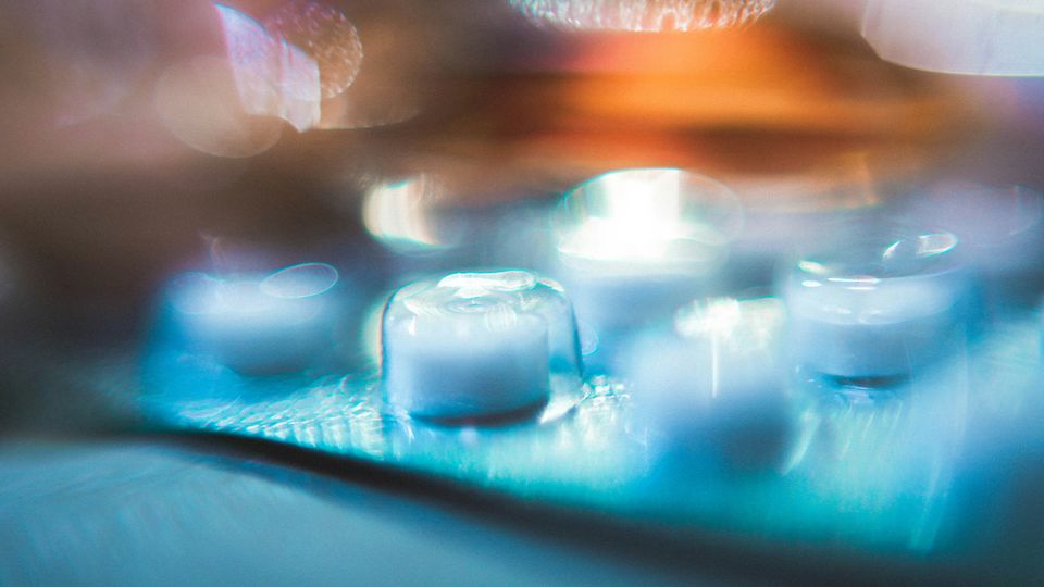 A blurry picture of pills still in their transparent plastic capsules in a packet.