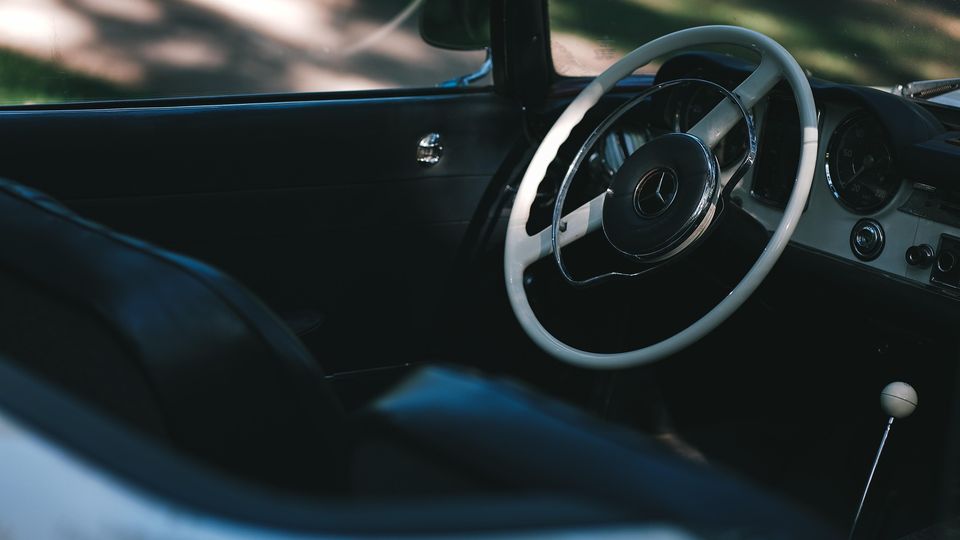 Interior of a classic car with steering wheel and seats, symbolizing travel and car sickness.