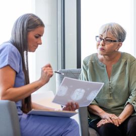 Female doctor discussing brain scan results with senior woman during Alzheimer's consultation. 