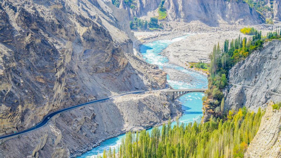 A valley in Pakistan, river, bridge and trees visible.