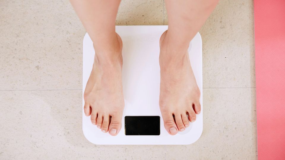 Person standing on a digital scale measuring body weight changes.