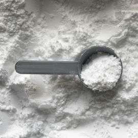 Scoop of white creatine powder supplement on a textured surface. 