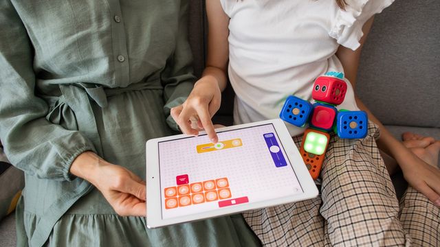 Child using a tablet with educational apps and toy blocks, supporting autism learning therapy. 