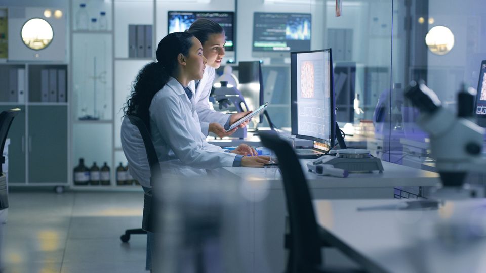Scientists in a laboratory analyzing computer data for drug discovery research.