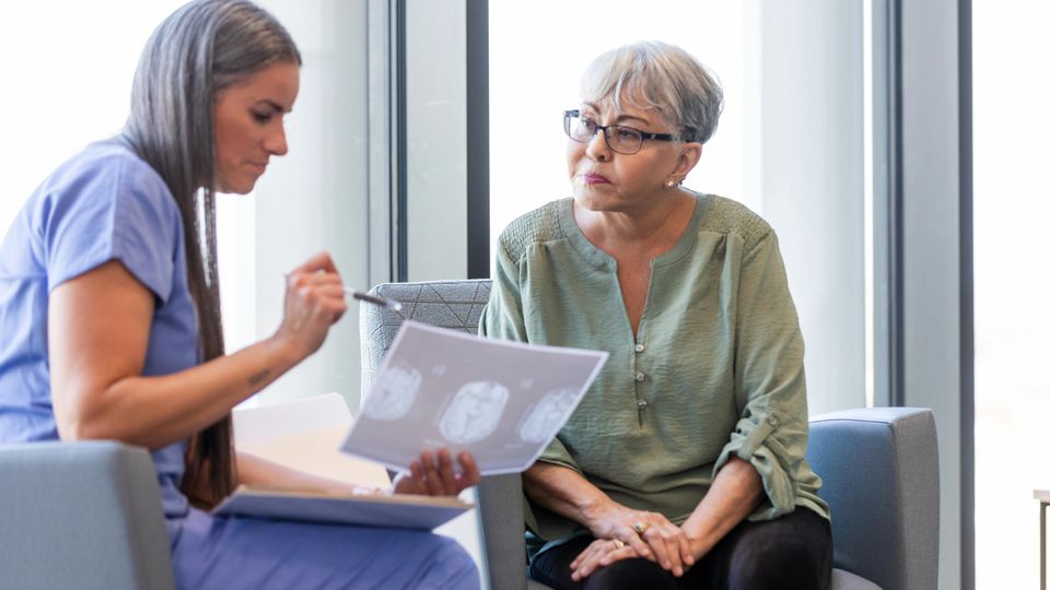 Doctor discussing brain scan results with an older woman during a dementia consultation.
