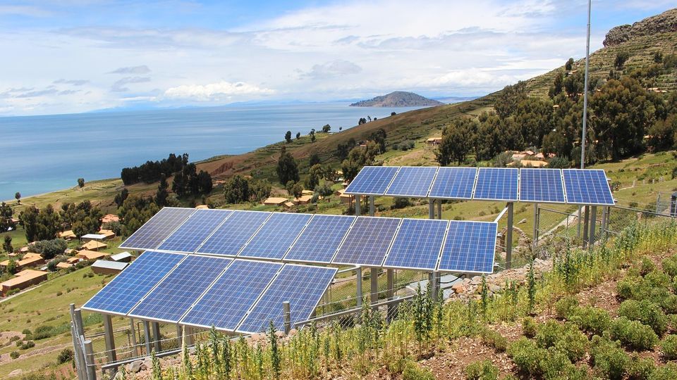 Solar panels on the side of a coastal hill.