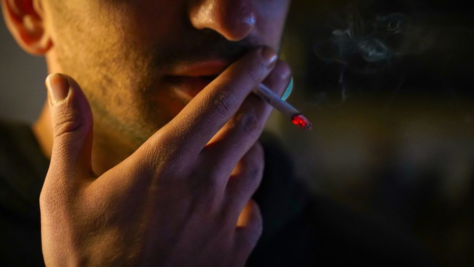 A young man smoking in the dark.