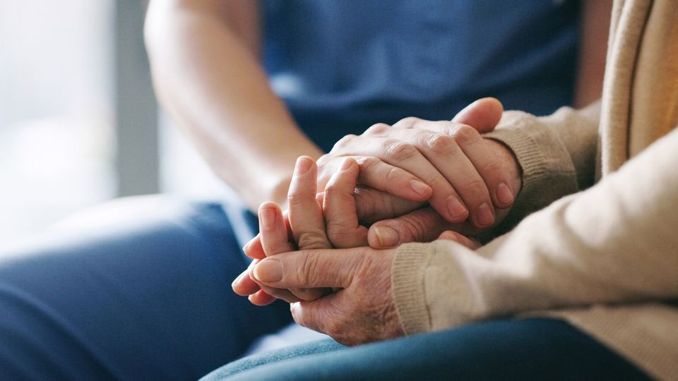 A doctor holding an older persons hands.